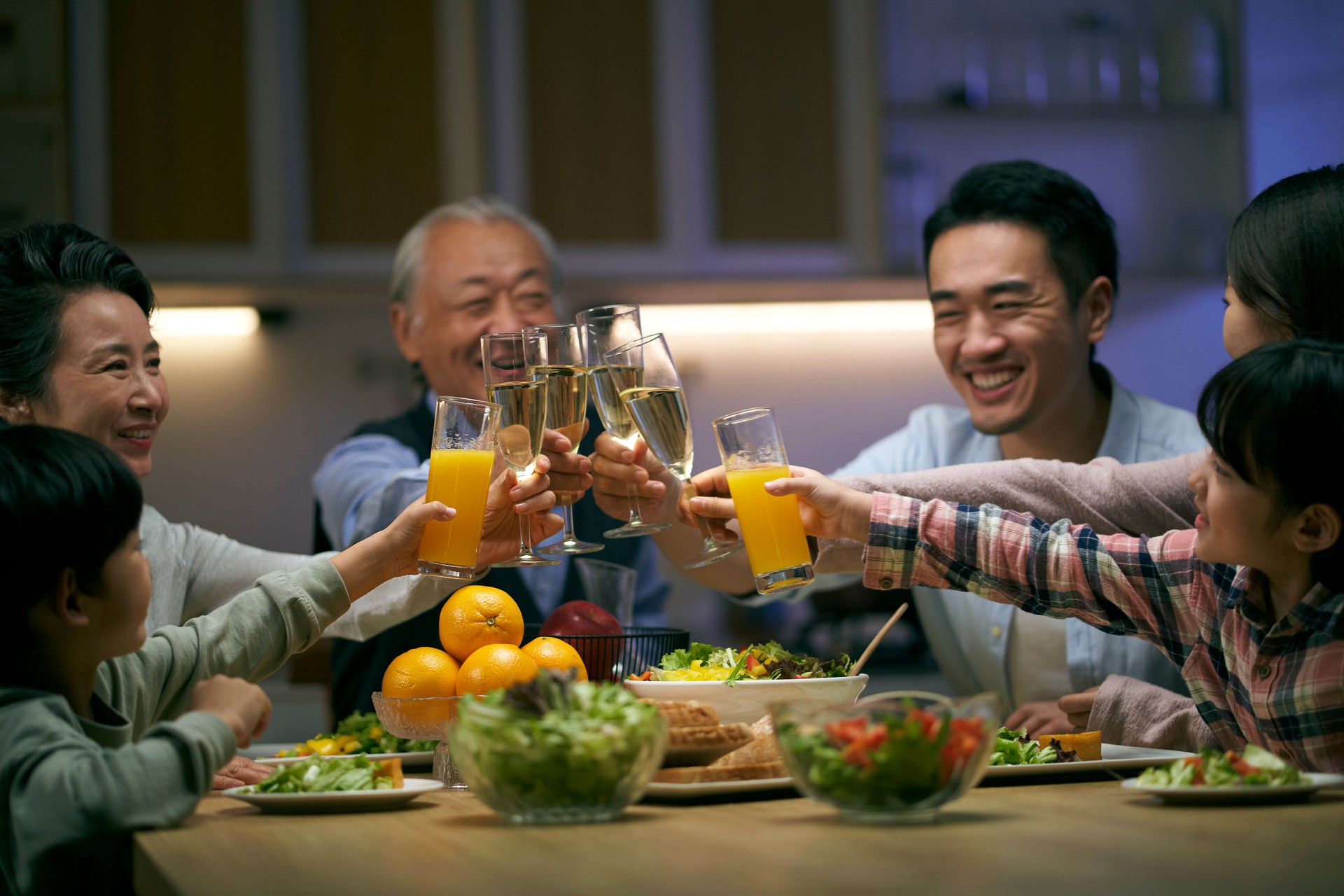 three generation asian family toasting while having dinner together