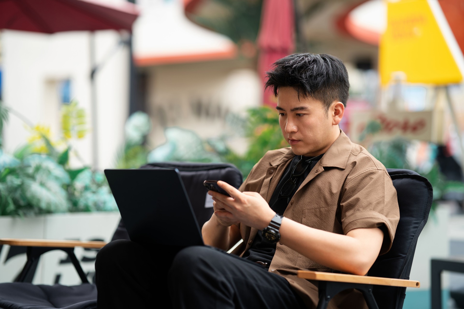 Asian handsome man sitting on a chair in a coffee shop beside the city street